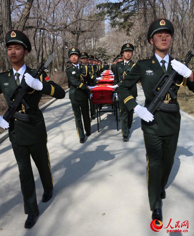 在韓志願軍烈士遺骸安葬儀式開始后，來自沈陽軍區某部的18名禮兵，托舉著覆蓋國旗的烈士遺骸棺槨緩緩走進現場。李祥輝攝 (
