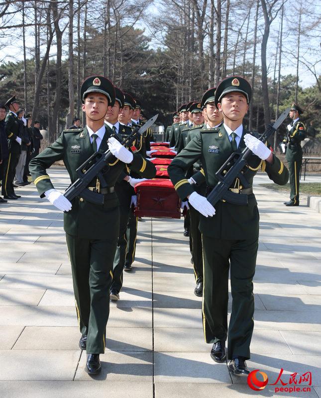 在韓志願軍烈士遺骸安葬儀式開始后，來自沈陽軍區某部的18名禮兵，托舉著覆蓋國旗的烈士遺骸棺槨緩緩走進現場。李祥輝攝 