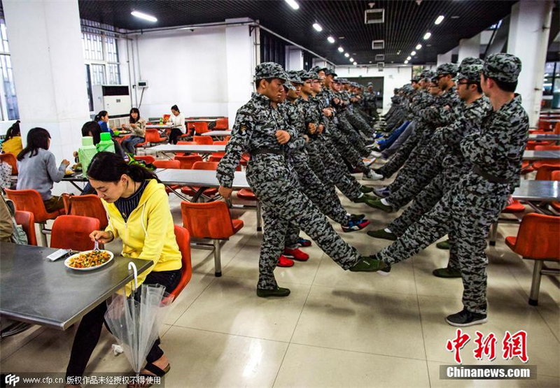 河南財經政法大學14級新生在該校第二餐廳內進行軍事訓練，學長學姐在旁邊淡定吃飯。