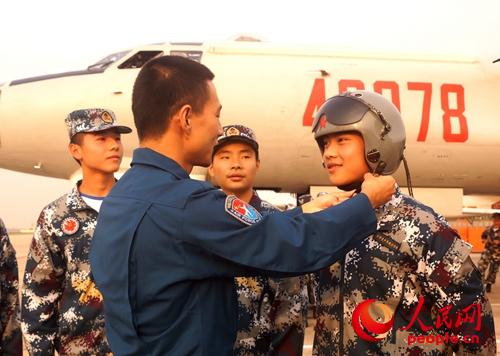 10月17日，空軍青少年航空學校西安中學航空實驗班學生，參觀空軍航空兵某團，圖為飛行員給學生馬曉辰試戴飛行頭盔。（申進科 攝）