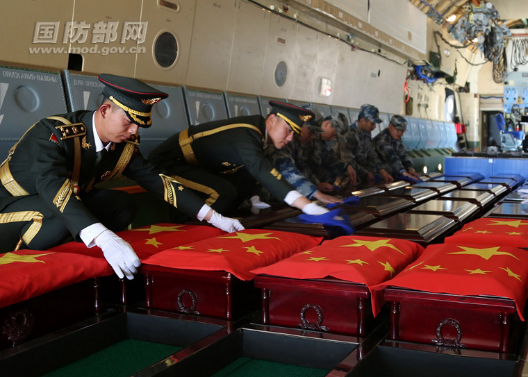 圖為禮兵和機組人員清除志願軍烈士棺槨灰塵覆蓋國旗。穆可雙 攝
