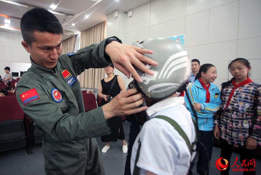 飛行員大關中學附小幫助小學生試戴頭盔。
