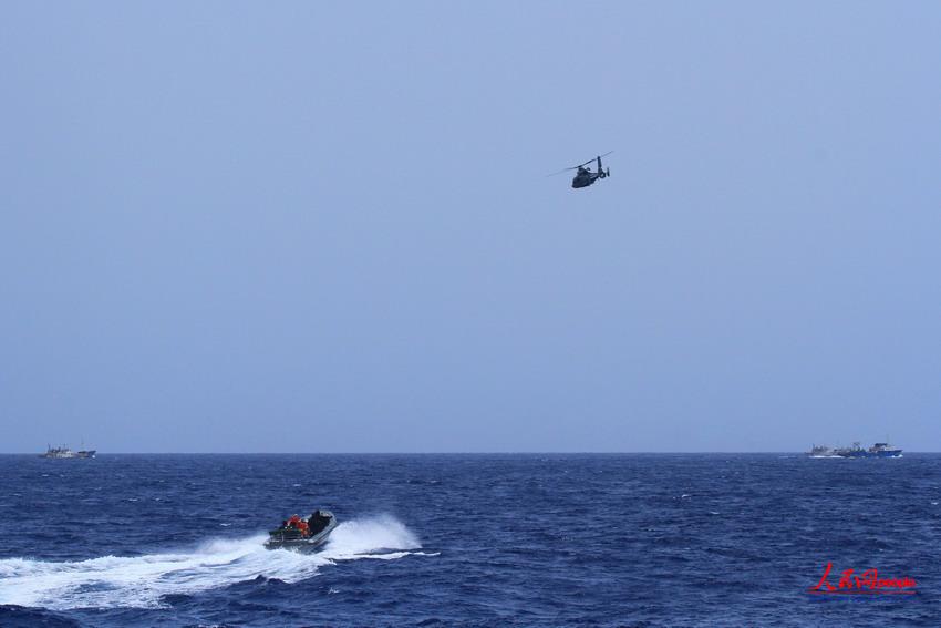 圖為特戰隊員乘小艇前往被護漁船，同時直升機升空進行巡邏警戒   謝坤攝