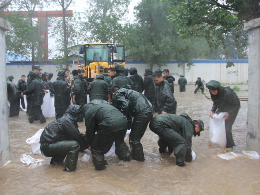 武警官兵奮力加固駐地小區堤壩。