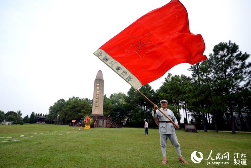 58歲的楊華在瑞金市紅色景區揮舞中國工農紅軍軍旗，向游客講解紅色革命歷史。