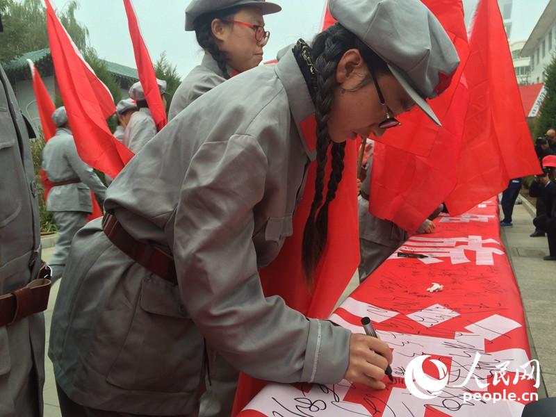 “保護紅色遺產·發展紅色旅游”萬人簽名儀式上，身著紅軍服飾的群眾正在簽名。柴秋實 攝