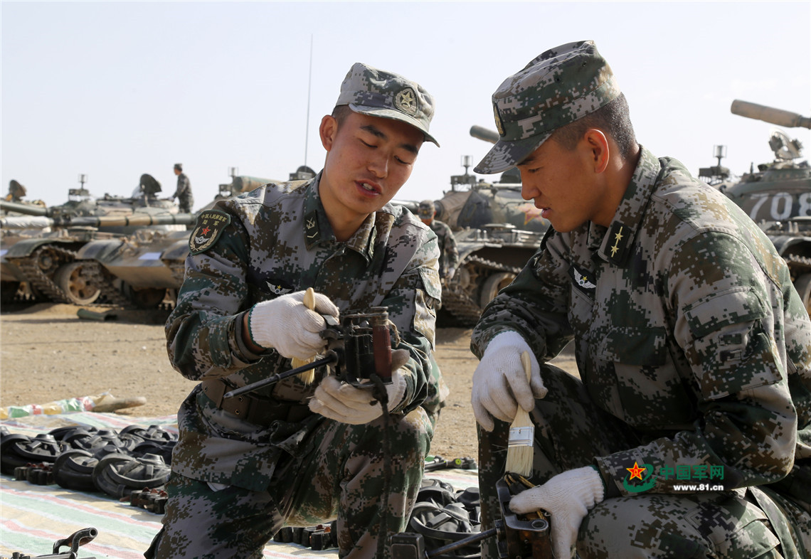 士官吳小凱（左）教排長楊金飛（右）機槍擦拭保養的方法。