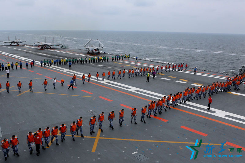 6月30日，遼寧艦官兵在飛行甲板進行起飛前異物排查。新華社記者 曾濤 攝
