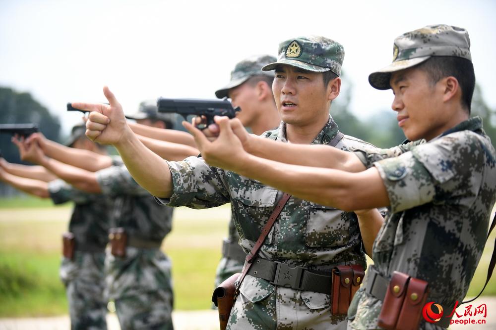 王銳（右二）組織手槍瞄准訓練，向戰友分享射擊瞄准經驗。彭希 攝