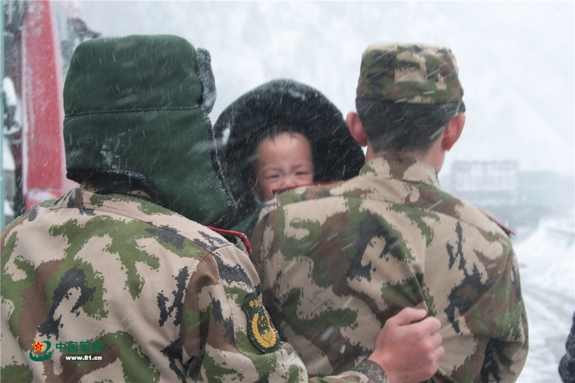 風雪太大，官兵用軍大衣緊緊把孩子裹在懷裡。李光印 攝