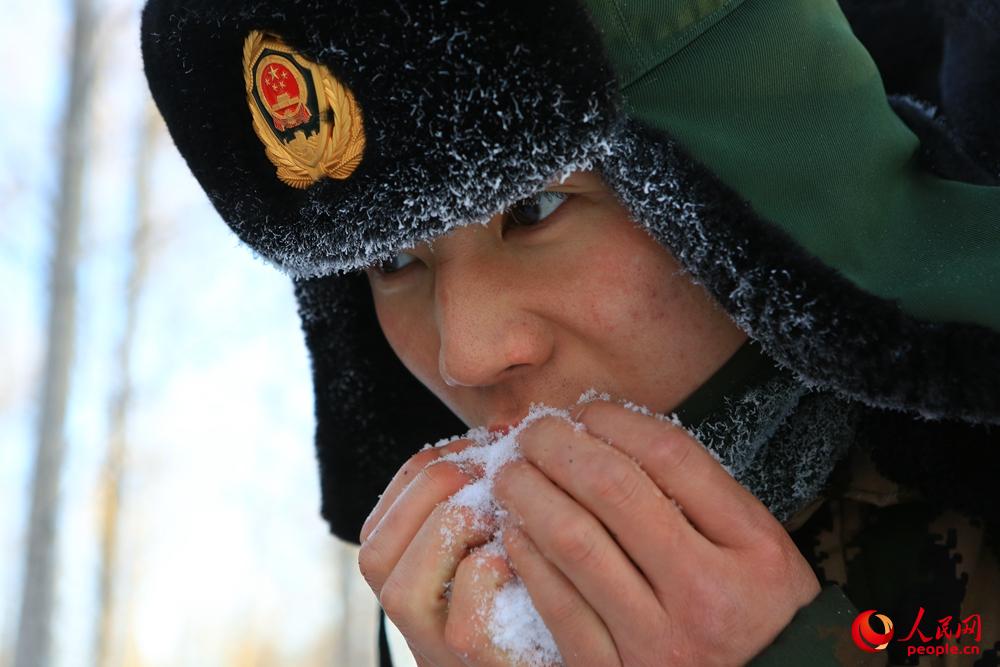 1月3日，武警內蒙古大興安嶺森林支隊戰士張政雷在行軍途中口渴難忍，抓起一把雪送進口中解渴。