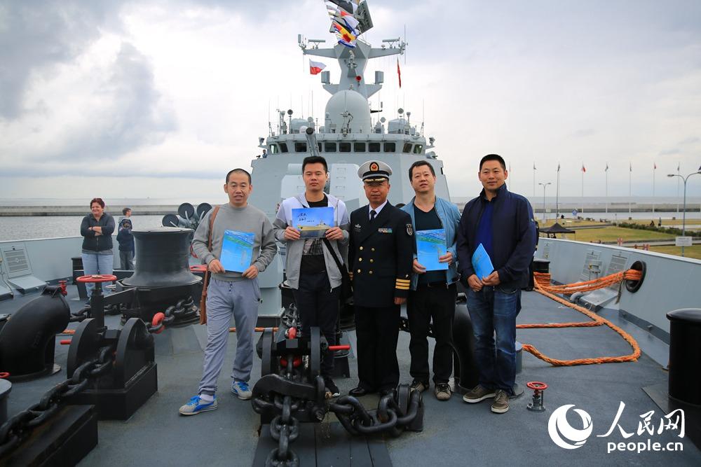 濱州艦政委蘇勤豐給上艦參觀的華人華僑送上濱州艦簽名照並與他們合影留念  韓林攝