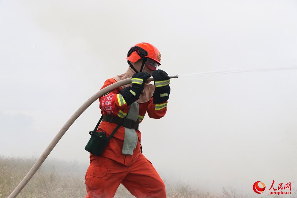 一名水泵手緊握水槍頭、在濃煙中進行以水滅火。