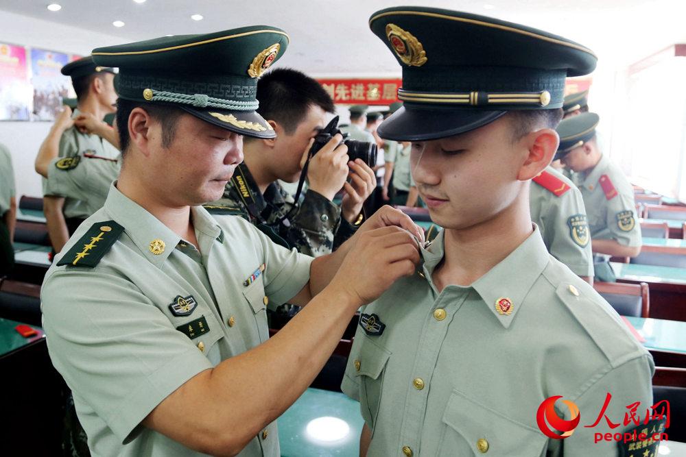 在宣布退役命令后中隊干部為一名老兵卸下肩章、領花等標志服飾。姜潤邈攝