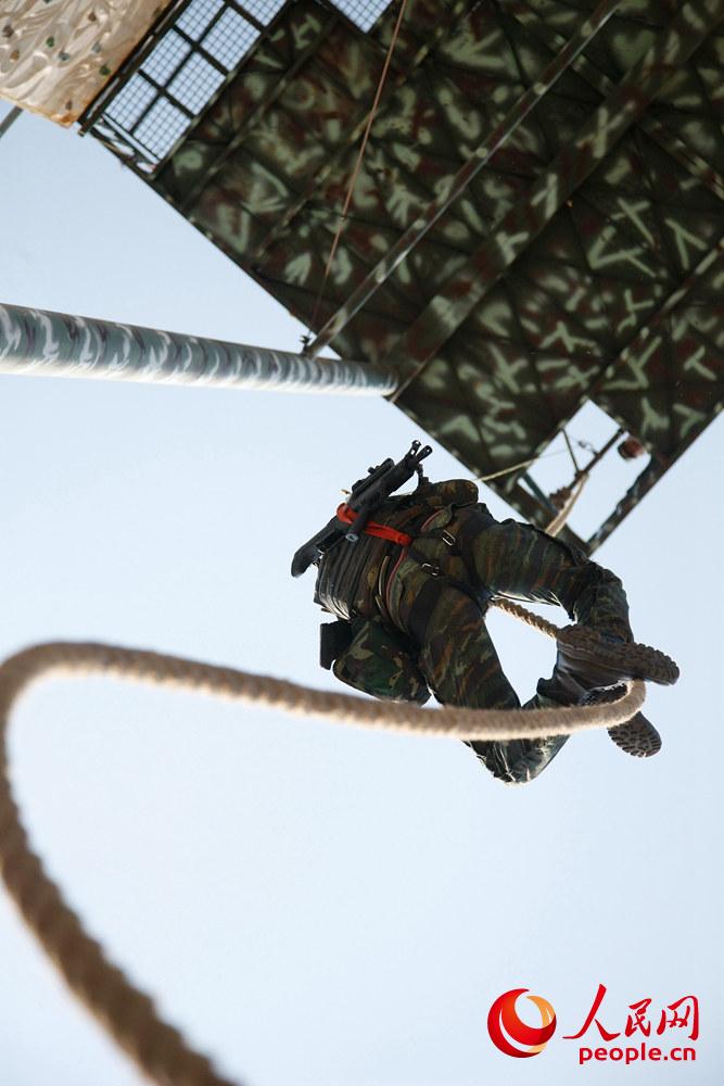 9月26日，在個人全能課目中，參賽隊員利用大繩攀爬至樓頂進行射擊。王濤攝