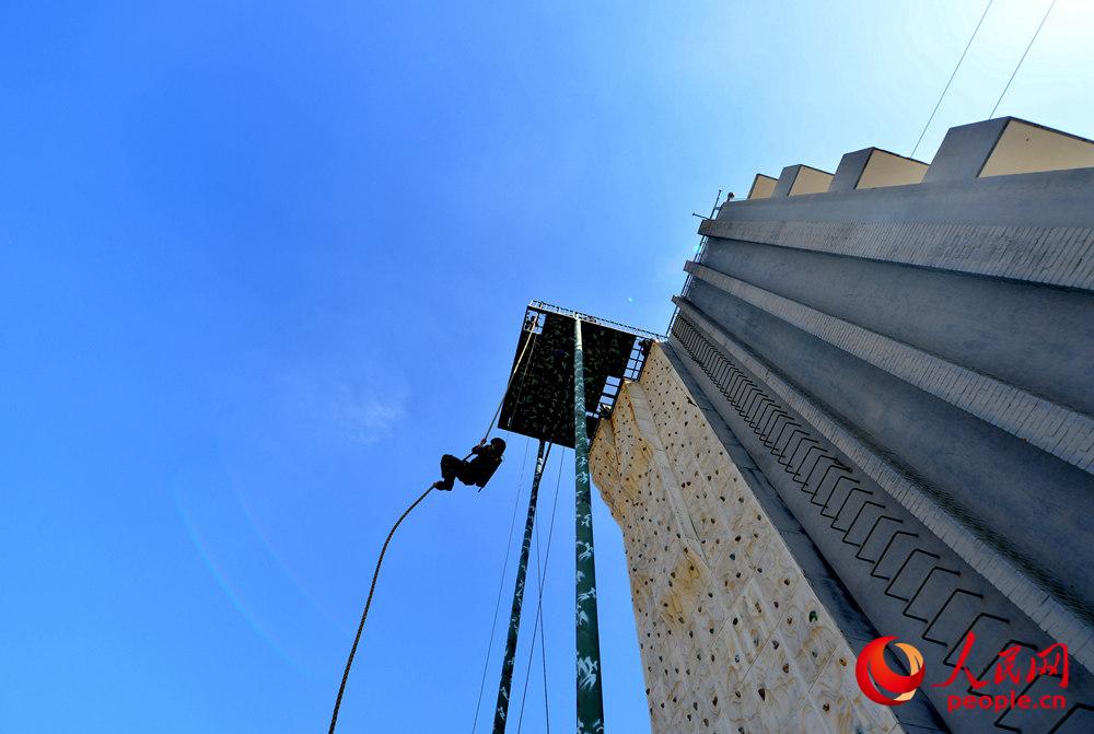 9月28日，在個人全能課目中，一名參賽隊員採取抓繩上的方式攀登至樓頂進行射擊。曹峰攝 