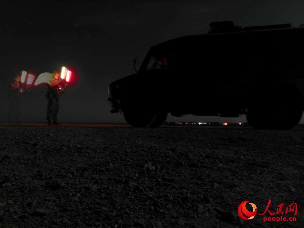 夜間，引導員利用熒光棒引導車輛。