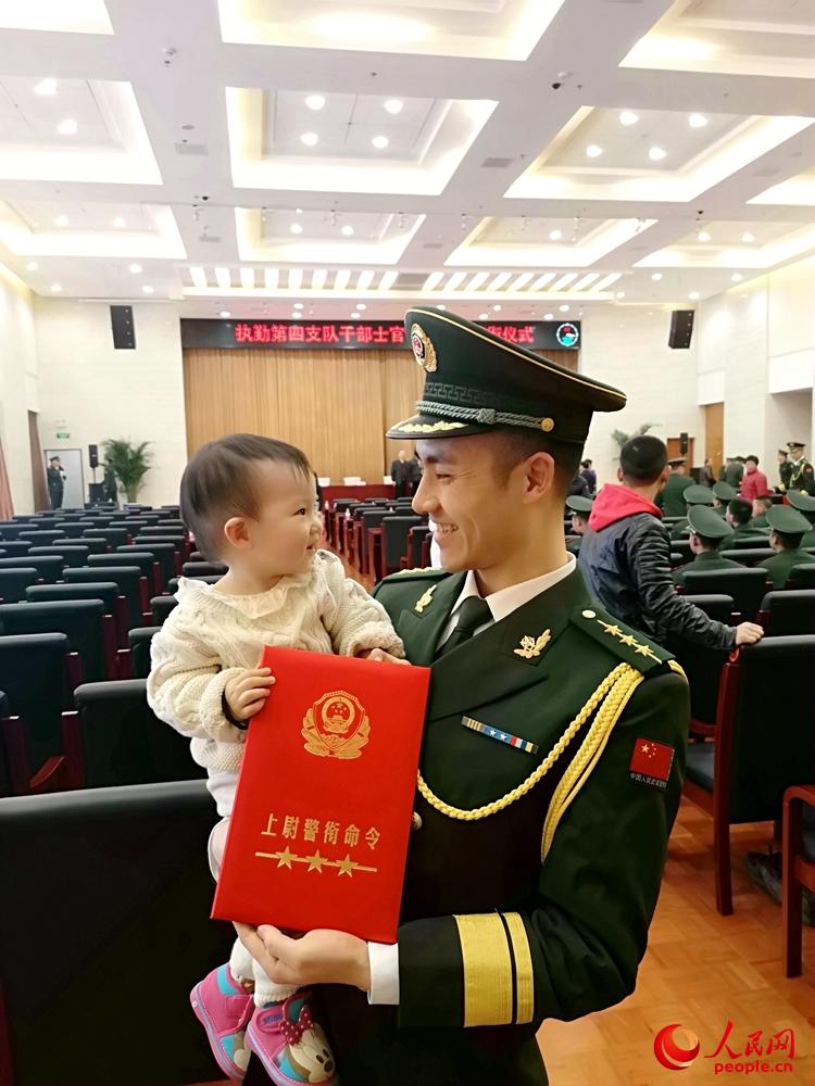 授銜儀式結束后懷抱女兒手拿命令狀的武警上尉。姜潤邈 攝