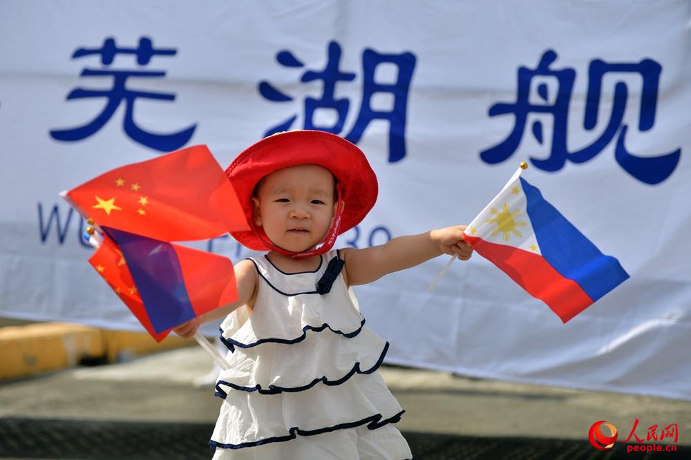 菲兒童在蕪湖艦舷梯前揮舞著中菲兩國小國旗。張海龍 攝