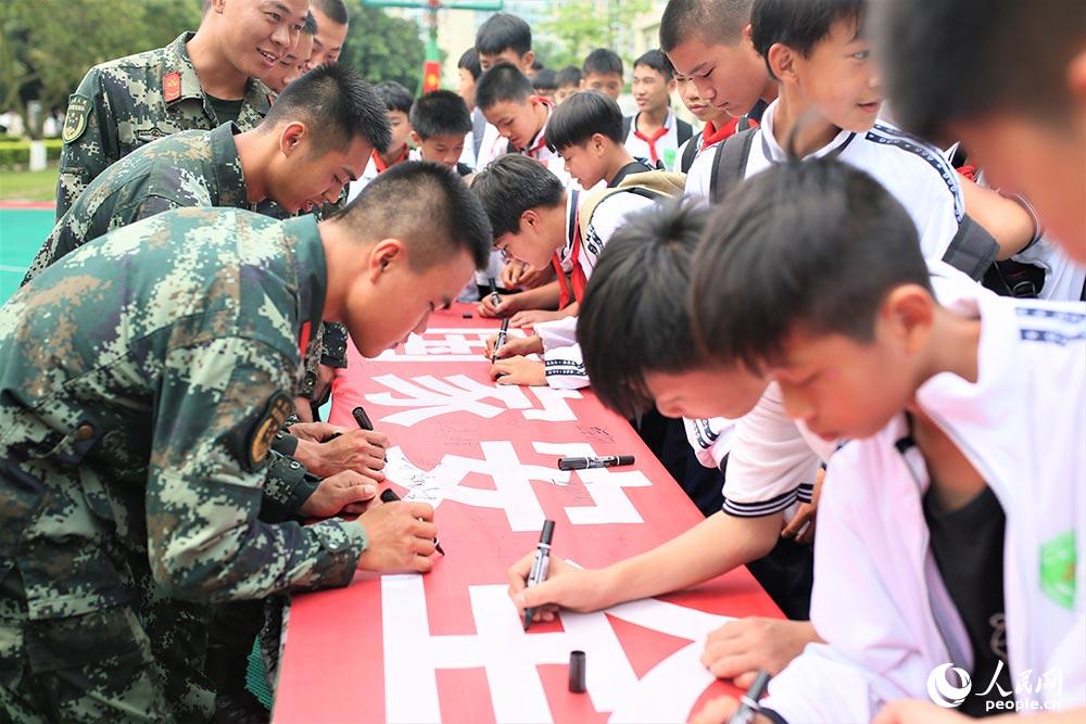 武警官兵和學生們一同在“國家安全、人人有責”的橫幅上簽名留念。
