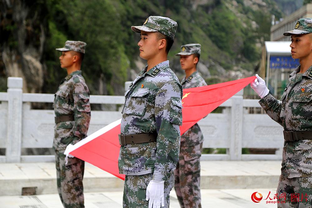 巡邏官兵在國門展示國旗。人民網記者閆嘉琪 攝 