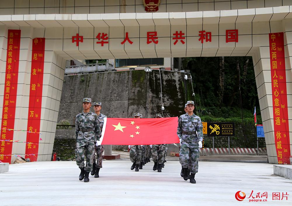 巡邏官兵在國門展示國旗。人民網記者閆嘉琪 攝