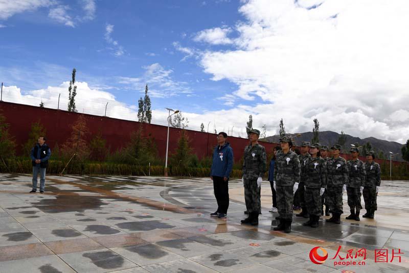 人民網採訪分隊人員與部隊官兵肅立在革命烈士紀念碑前瞻仰默哀。 王乾攝
