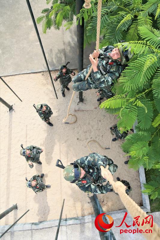 兩名武警官兵在進行抓繩攀登比拼。