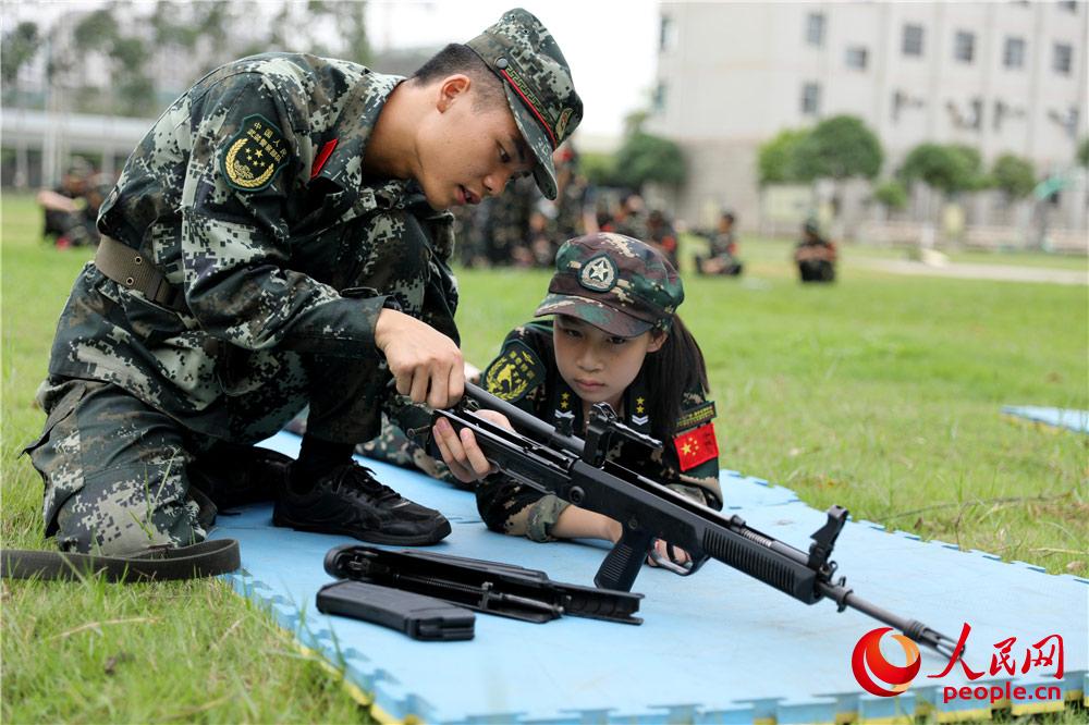 在武警百色支队训练场，武警战士向“萌娃”介绍步枪结构。