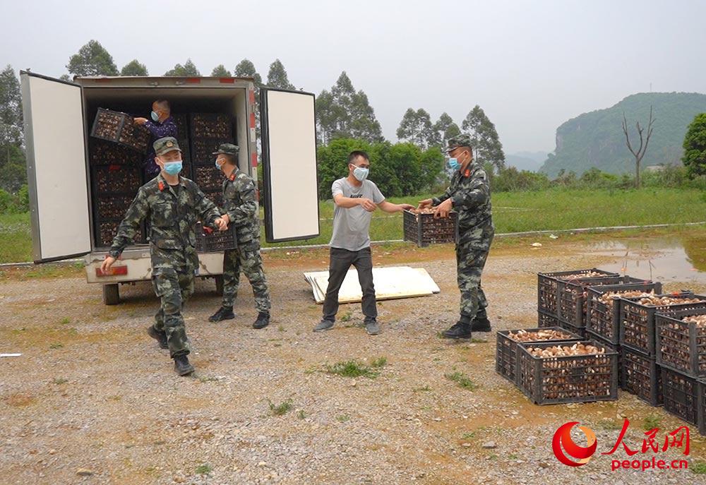 官兵帮助村民搬运香菇。