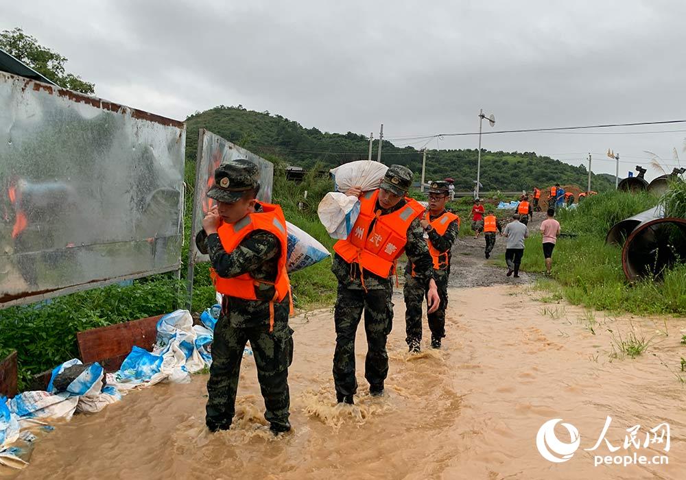 救援官兵正在搬运沙袋加固河堤