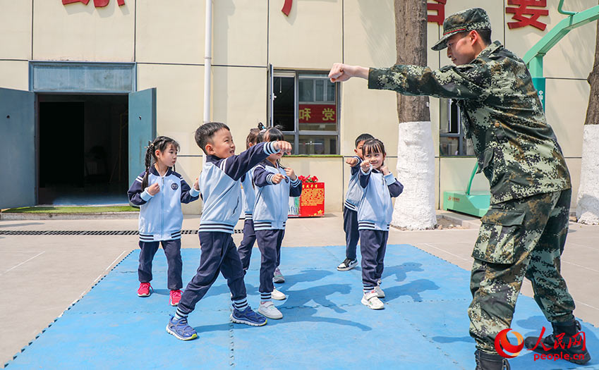 武警官兵向小朋友展示格斗技巧。
