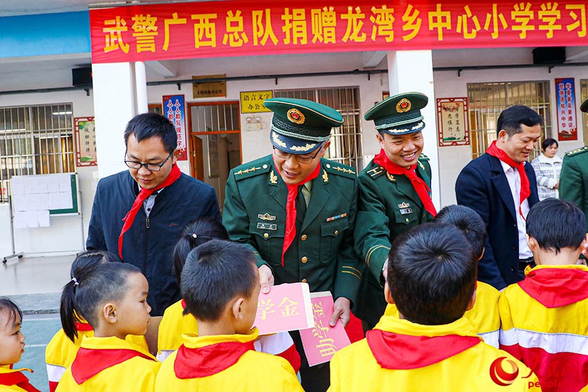 武警官兵给总队定点帮扶对象――琴棋村家庭困难的学生发放助学金。
