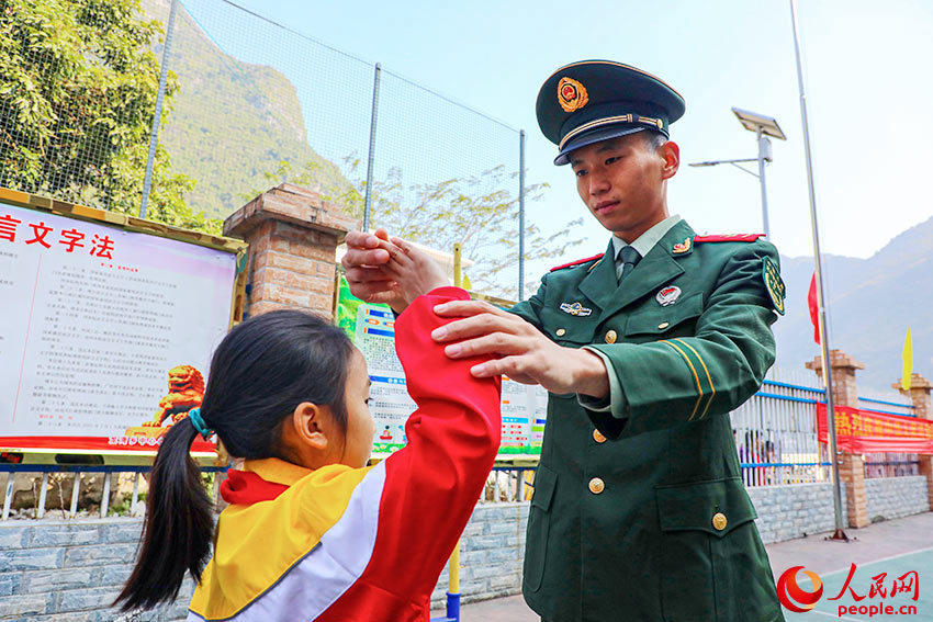 武警官兵帮助学生规范敬礼动作。