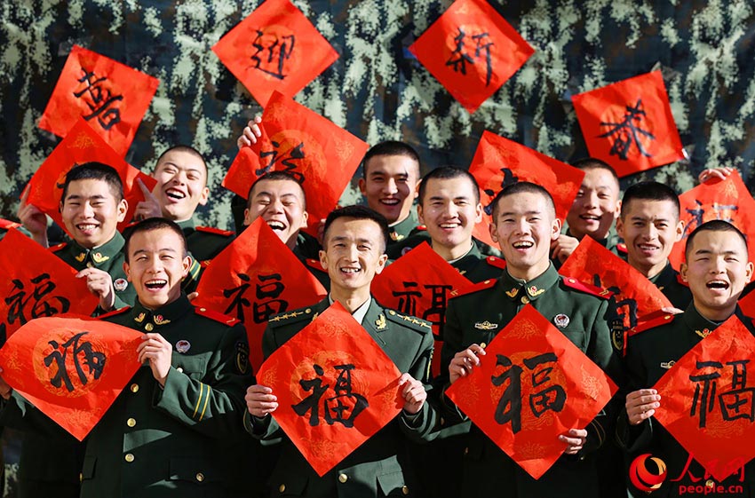 官兵們展示著手中的“福”字，臉上洋溢著燦爛的笑容。
