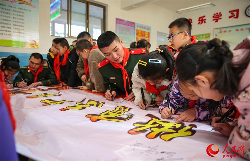 官兵和学生共同在倡议横幅上签字。