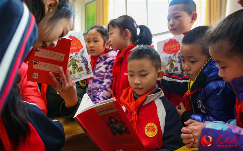 小學生們閱讀雷鋒故事書籍。