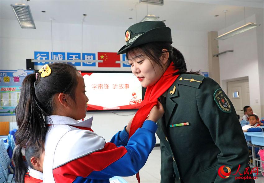 小學生為官兵佩戴紅領巾。