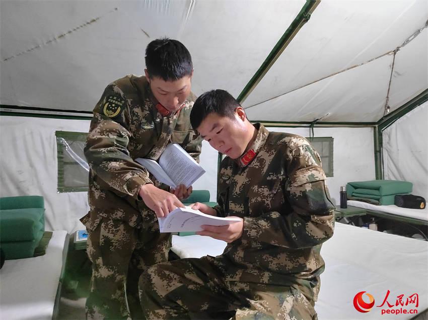 参训学兵在帐篷宿舍交流学习专业理论知识。
