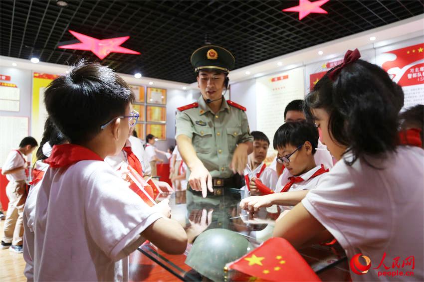 在中队荣誉室内，武警官兵向孩子们讲述红色战斗故事。