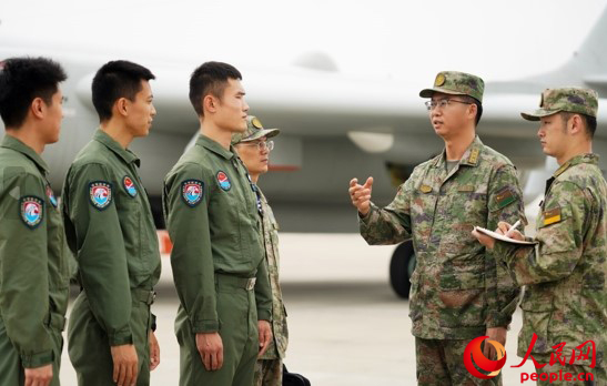 秦明在某机场与飞行人员探讨交流。一名上校沉着冷静，这是他一贯的战斗作风�，他决心在联合作战指挥的舞台上一显身手。张先瑞 摄</p><p style=