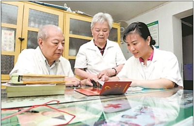 上图：彭天冰与父母一起讨论医疗义诊活动方案。石祯专 摄