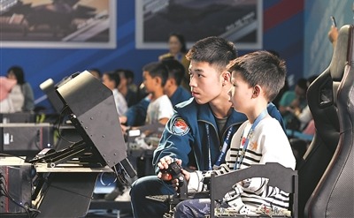 九月二十日，第十一届空军航空开放活动和长春航空展现场，一名小朋友在飞行学员帮助下进行空战模拟对抗操作。余红春摄
