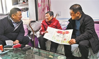 退役军人事务局工作人员为怀允英（中）送上其父的烈士证明书。张建军摄