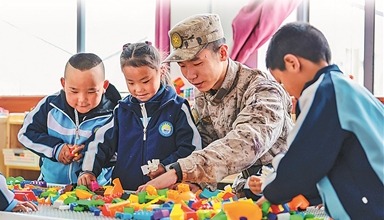 新疆軍區某團組織開展“民族團結一家親”活動。圖為在駐地村庄幼兒園，一名戰士和小朋友們一起拼積木。袁存皓攝