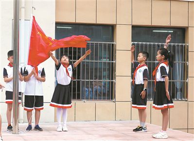 安徽省安庆市华中路第一小学升旗仪式上，师生们升起国旗。方 迪摄